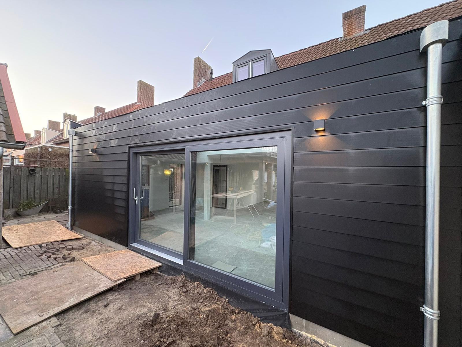 Uitbouw woonkamer – afgeronde aanbouw met zwarte gevelbekleding